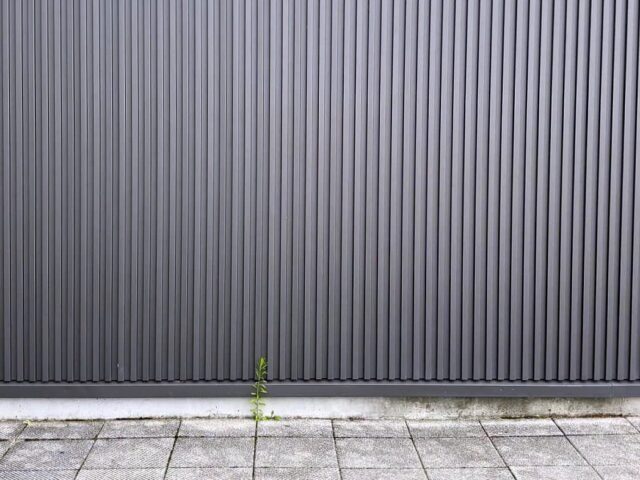 縦に溝の入った金属の外壁材を張った家の壁